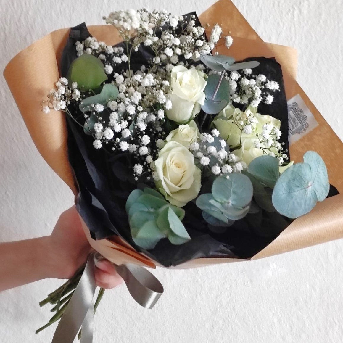 Starry Night. Bouquet of white roses and gypsophila in dark package